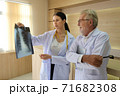 Two doctors are looking at the patient's history and X-Ray film and discussing the patient's illness. 71682308