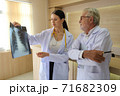 Two doctors are looking at the patient's history and X-Ray film and discussing the patient's illness. 71682309