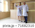 Two doctors are looking at the patient's history and X-Ray film and discussing the patient's illness. 71682310