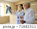 Two doctors are looking at the patient's history and X-Ray film and discussing the patient's illness. 71682311