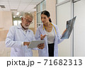 Two doctors are looking at the patient's history and X-Ray film and discussing the patient's illness. 71682313