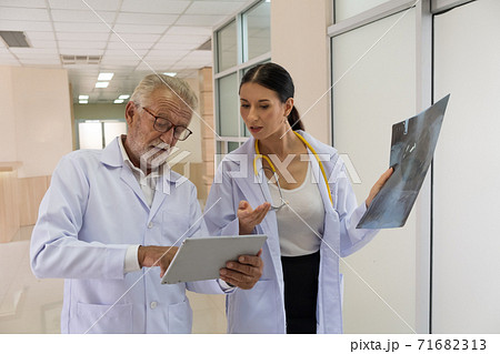 Two doctors are looking at the patient's history and X-Ray film and discussing the patient's illness. Two doctors are looking at the patient's history and X-Ray film and discussing the patient's illness. 71682313