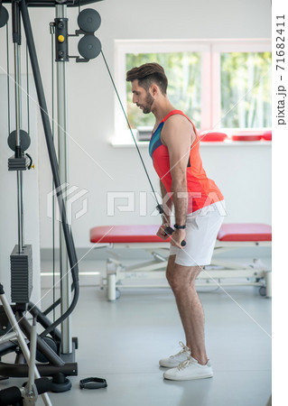 Young dark-haired man pulling the ropes and looking concentrated 71682411