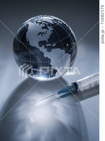 Glass globe and syringe on gray background Glass globe and syringe on gray background 71682570