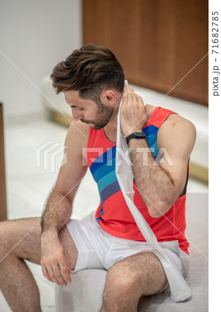 Sportsman in bright tshirt sitting and wiping himself with a towel Sportsman in bright tshirt sitting and wiping himself with a towel 71682785