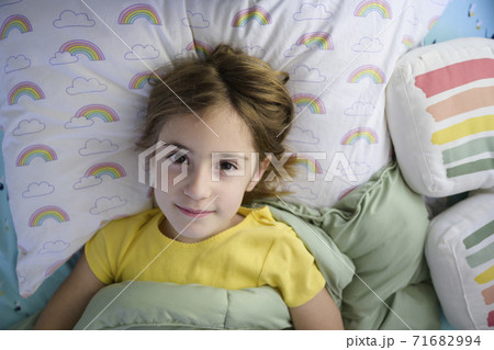 Portrait of girl (6-7) lying in bed 71682994