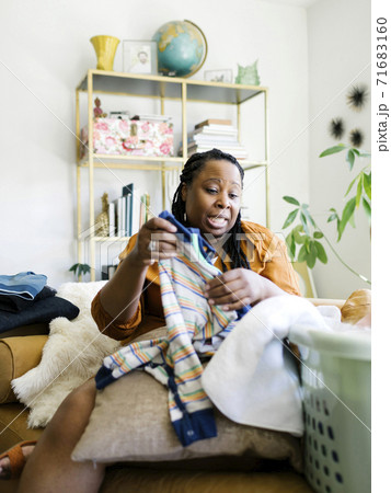 Woman folding baby clothing at home 71683160