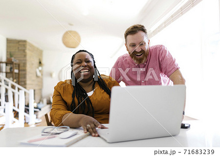 Man and woman looking at laptop at desk in home office 71683239