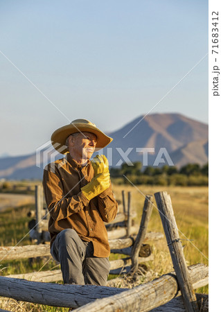 USA, Idaho, Bellevue, Rancher standing by fence and putting on gloves USA, Idaho, Bellevue, Rancher standing by fence and putting on gloves 71683412