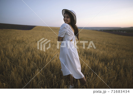 France, Young woman in white dress standing in cereal field France, Young woman in white dress standing in cereal field 71683434