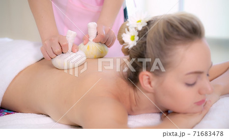 Massage therapist using herbal compress with woman Massage therapist using herbal compress with woman 71683478