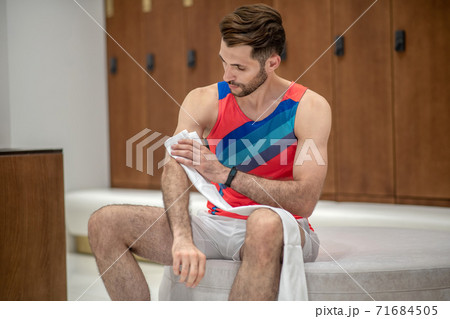 Sportsman in bright tshirt wiping himself with a towel Sportsman in bright tshirt wiping himself with a towel 71684505