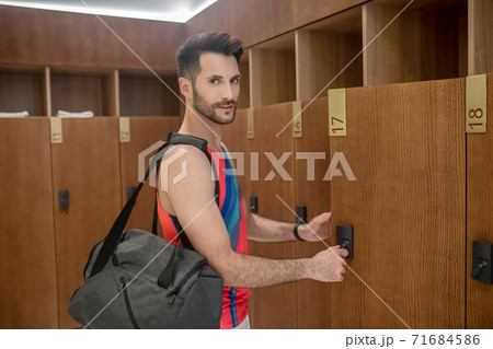 Young man in bright tshirt opening the locker Young man in bright tshirt opening the locker 71684586