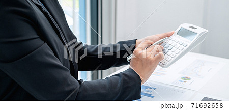 Business woman are working by reviewing the numeric data from the graph using a calculator Business woman are working by reviewing the numeric data from the graph using a calculator 71692658