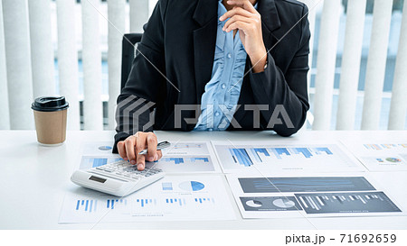 Business woman are working by reviewing the numeric data from the graph using a calculator Business woman are working by reviewing the numeric data from the graph using a calculator 71692659