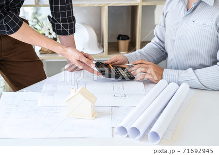 Construction engineering or architect discussing a blueprint and building model while checking information on sketching meeting for architectural project in work site Construction engineering or architect discussing a blueprint and building model while checking information on sketching meeting for architectural project in work site 71692945