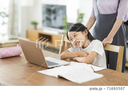 パソコンで勉強をする女の子と母親の写真素材