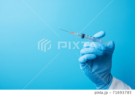 Hand of doctor injection vaccine or drug by Needle Syringe on blue background in hospital laboratory. Medical, health Insurance, Vaccination and immunization concept Hand of doctor injection vaccine or drug by Needle Syringe on blue background in hospital laboratory. Medical, health Insurance, Vaccination and immunization concept 71693785