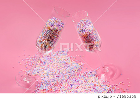 Champagne glasses filled with colorful sugar balls on pink background. Glasses filled with rainbow colored candies, sweet holidays concept. Celebration minimal Christmas party. Champagne glasses filled with colorful sugar balls on pink background. Glasses filled with rainbow colored candies, sweet holidays concept. Celebration minimal Christmas party. 71695359