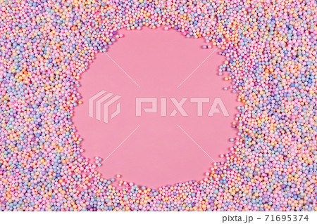 Round frame made of pastel color balls on pink. Styrofoam or Polystyrene foam background. Mix of colorful sugar balls for sweets decoration. Rainbow colored sugar chips, dragee spins, confectionery. Round frame made of pastel color balls on pink. Styrofoam or Polystyrene foam background. Mix of colorful sugar balls for sweets decoration. Rainbow colored sugar chips, dragee spins, confectionery. 71695374