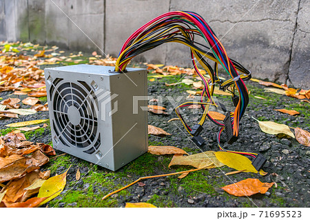 Computer power supply lying outdoors in autumn foliage at landfill 71695523