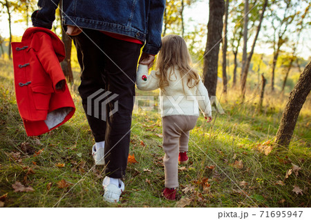 Happy father and little cute daughter walking down the forest path in autumn sunny day Happy father and little cute daughter walking down the forest path in autumn sunny day 71695947