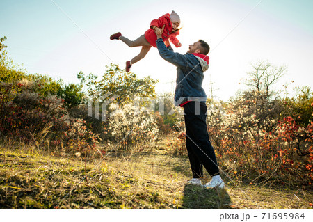 Happy father and little cute daughter walking down the forest path in autumn sunny day 71695984