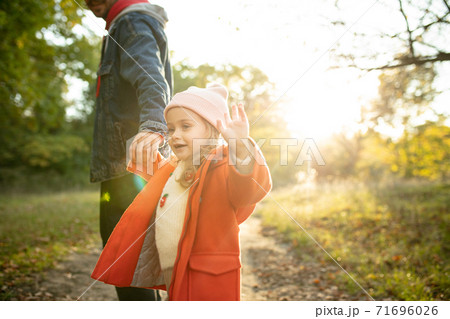 Happy father and little cute daughter walking down the forest path in autumn sunny day Happy father and little cute daughter walking down the forest path in autumn sunny day 71696026