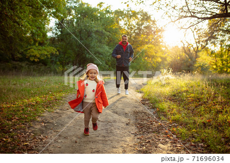 Happy father and little cute daughter walking down the forest path in autumn sunny day 71696034