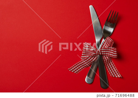 Cutlery with checkered bow on red background Cutlery with checkered bow on red background 71696488
