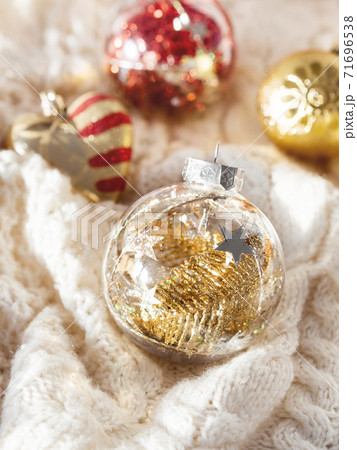 Decorative balls for Christmas tree on cable-knit sweater. Transparent sphere with red, golden spangles inside. Winter holiday spirit. New year celebration. 71696538