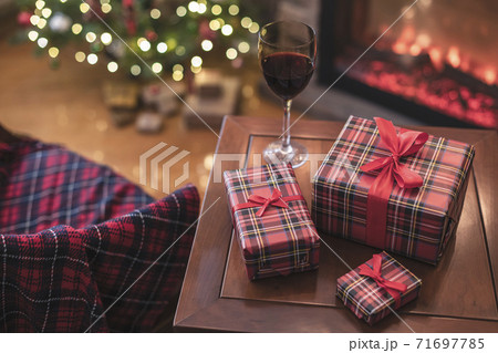 Armchair with plaid, packing gift boxes for family and glass of wine near christmas tree and fireplace. Top view Armchair with plaid, packing gift boxes for family and glass of wine near christmas tree and fireplace. Top view 71697785