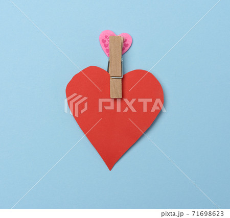 red paper heart pinned on a wooden clothespin, blue background red paper heart pinned on a wooden clothespin, blue background 71698623