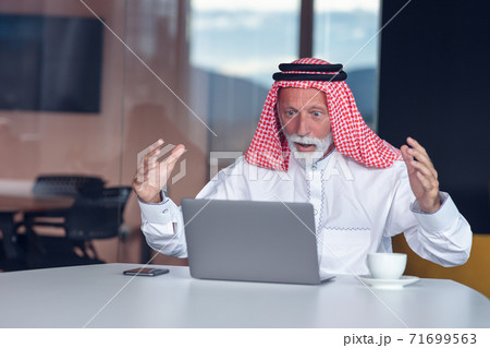 Arab businessman looks surprised while using a laptop Arab businessman looks surprised while using a laptop 71699563