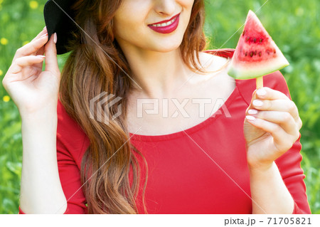 Fashionable young woman is holding a slice of watermelon. Fashionable young woman is holding a slice of watermelon. 71705821