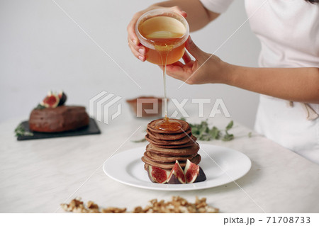 Cook pours honey on the pancakes. 71708733