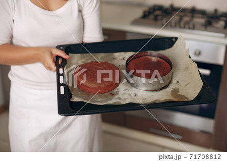 Confectioner takes the finished cake out of the oven. Confectioner takes the finished cake out of the oven. 71708812