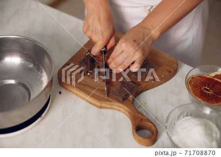 Confectioner cuts chocolate on a wooden board. 71708870