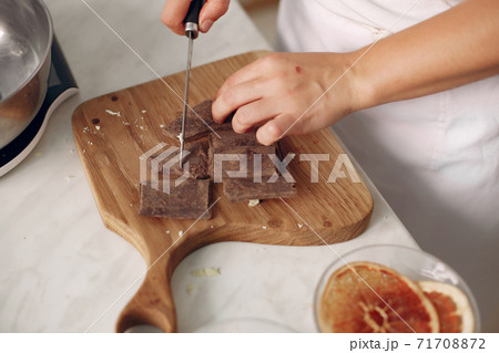 Confectioner cuts chocolate on a wooden board. 71708872