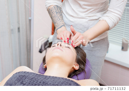 The master gives a facial massage to the client. 71711132