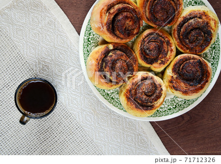 Plate of cinnamon rolls buns and cup of black coffee 71712326