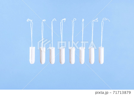 Flying tampons. Menstrual period concept. Woman hygiene protection. Women's health. Cotton tampons on blue background. Front view. Conceptual minimal still life. Flying tampons. Menstrual period concept. Woman hygiene protection. Women's health. Cotton tampons on blue background. Front view. Conceptual minimal still life. 71713879