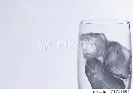 白を背景に水滴の付いたグラスに入った氷塊 71715694