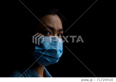Asian woman wearing protective mask isolated over background. Low key. Asian woman wearing protective mask isolated over background. Low key. 71720410