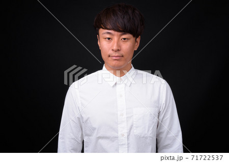 Young handsome Asian businessman against black background 71722537