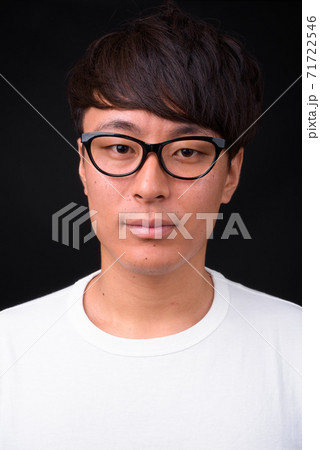 Young handsome Asian man against black background 71722546