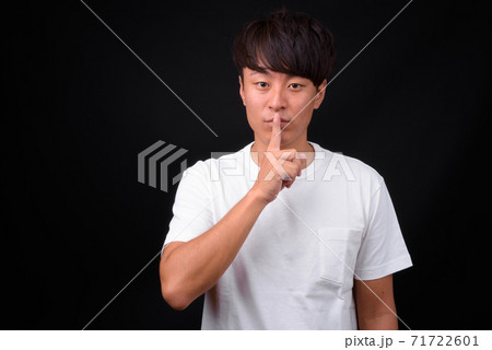 Young handsome Asian man against black background Young handsome Asian man against black background 71722601