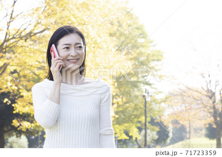 秋の公園でスマホで話すミドル女性 秋の公園でスマホで話すミドル女性 71723359