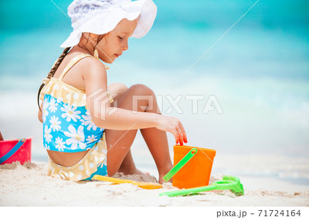 Little girl at tropical white beach making sand castle Little girl at tropical white beach making sand castle 71724164