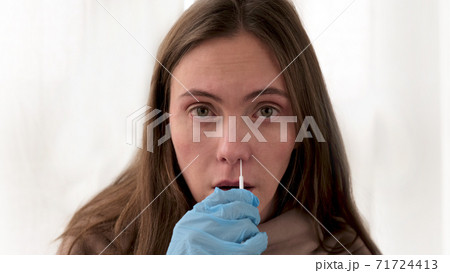 Woman takes swab from nasal mucosa using medical tampon 71724413